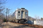 The eastbound NJT Princeton Dinky rounding the bend on the right of way bisecting the parking lot on the westbound side of Princeton Jct Station